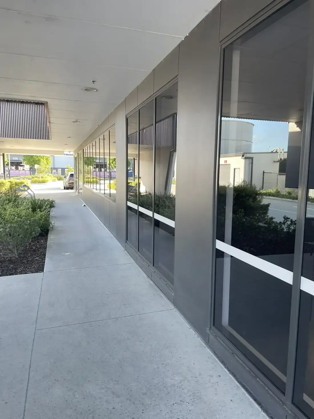 Curved commercial storefront glazing reflecting the sky after exterior clean