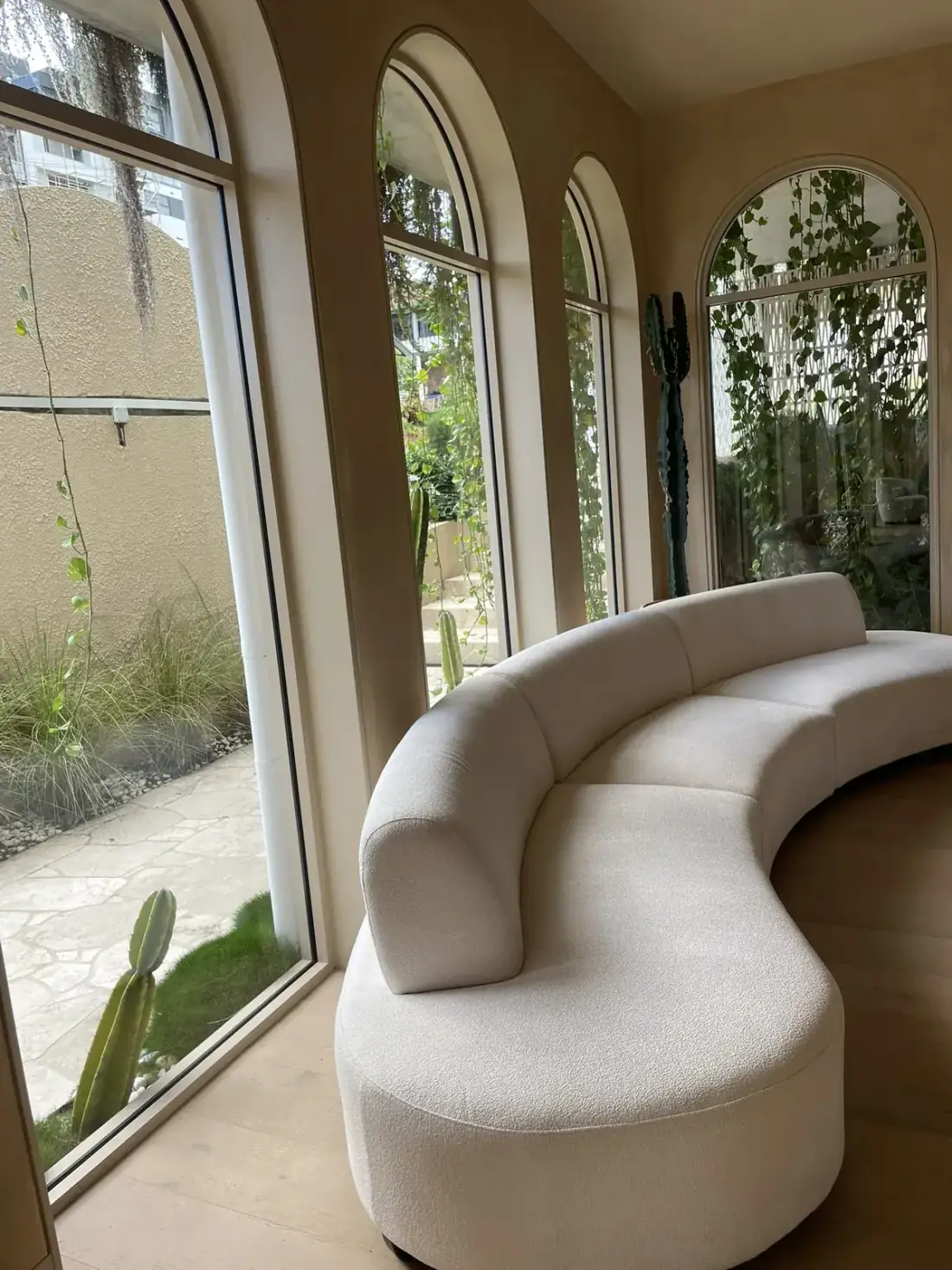 Arched picture windows beside a curved sofa with garden views